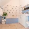 Modernes Badezimmer mit blauen Wänden, Badewanne, Waschbecken und goldenen Armaturen.