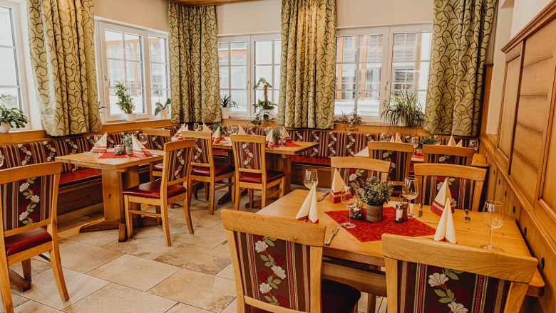 Gem&uuml;tliches Restaurant mit Holzm&ouml;beln, dekorierten Tischen und Pflanzen am Fenster.