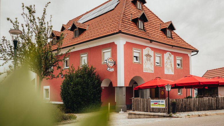 Ein rotes Gebäude mit roten Sonnenschirmen und Solarpanelen auf dem Dach.
