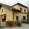 Gelbes Haus mit Terrasse und Menschen, die drau&szlig;en sitzen.