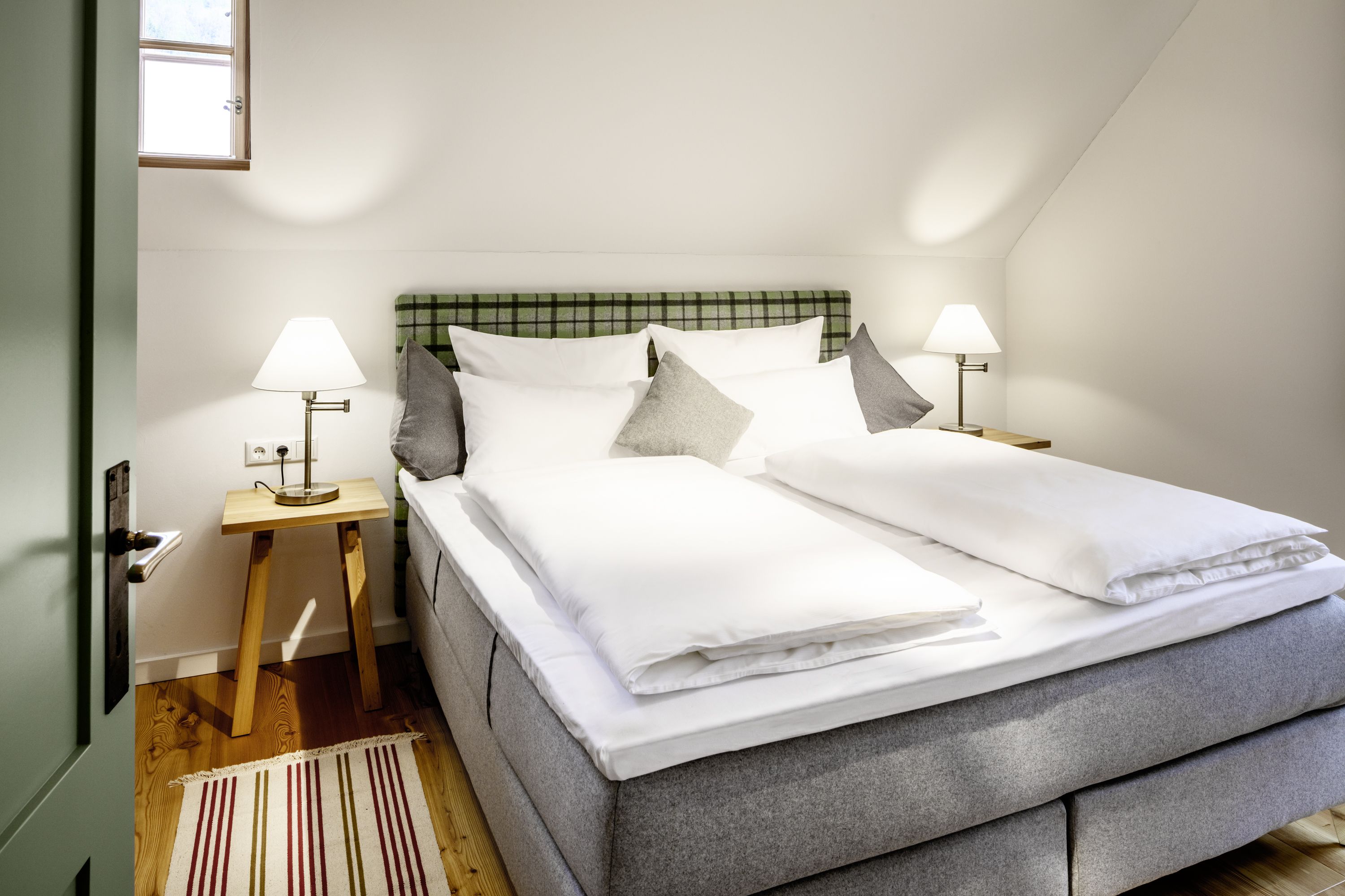 Gemütliches Hotelzimmer mit Doppelbett, Nachttischen und Lampen.