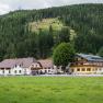 Gasthof Furtner vor bewaldetem Hügel.
