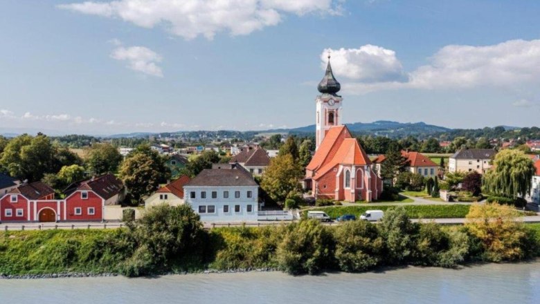 Landschaftsansicht von Persenbeug-Gottsdorf mit Kirche und Fluss im Vordergrund.