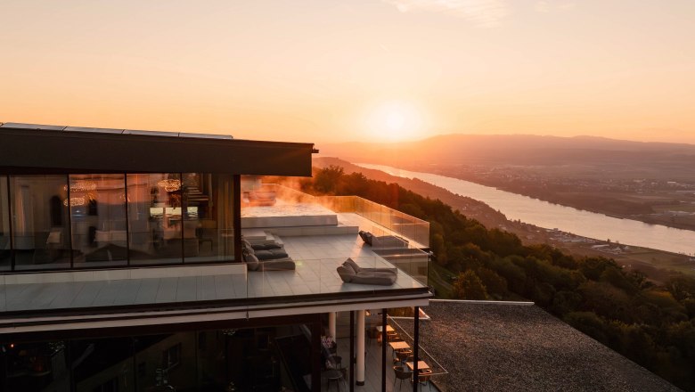 Modernes Hotel mit Terrasse und Flussblick bei Sonnenuntergang und Blick über die Donau.