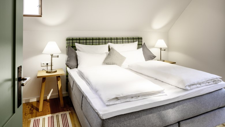 Gemütliches Hotelzimmer mit Doppelbett, Nachttischen und Lampen.