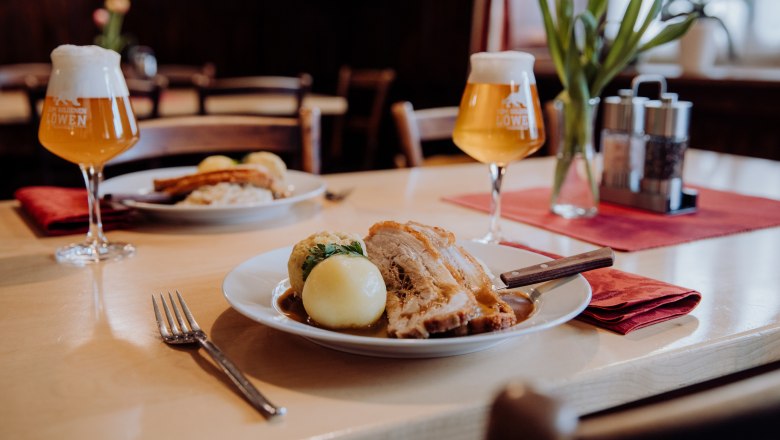 Schweinsbraten mit Knödel und Bier in einem gemütlichen Restaurant.