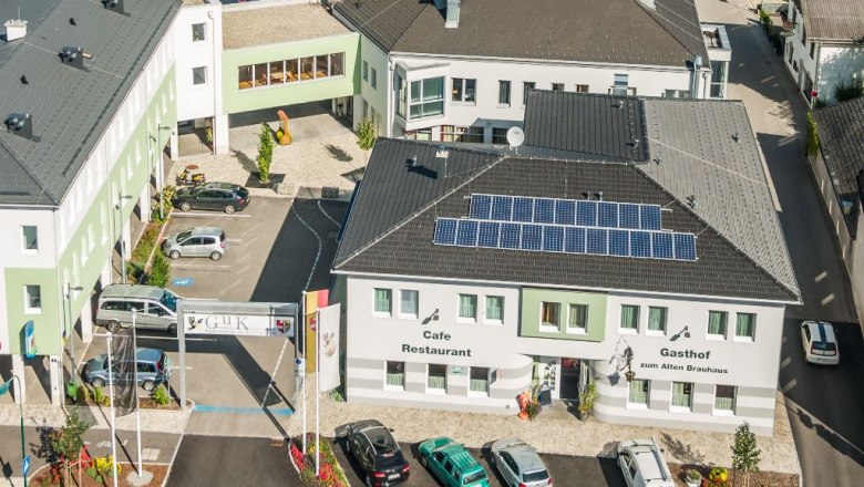 Luftaufnahme eines Gebäudekomplexes mit dem Gasthof zum Alten Brauhaus, Solarpanels auf dem Dach und mehreren geparkten Autos.