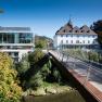 Moderne und historische Geb&auml;ude mit Br&uuml;cke in gr&uuml;ner Umgebung.