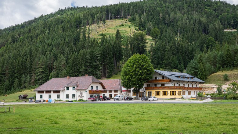 Gasthof Furtner vor bewaldetem Hügel.