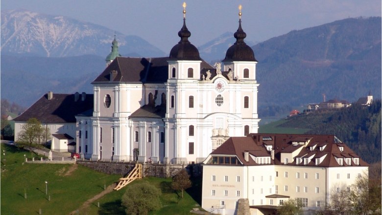 Basilika Sonntagberg auf einem Hügel mit Bergen im Hintergrund.