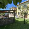 Garten mit Pavillon, gelbem Haus und Auto im Hintergrund.