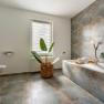 Modernes Badezimmer mit Badewanne, Pflanze und Fenster.