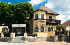 Eingang des Hotel Kaiser Franz Josef mit gelber Fassade und Balkon.