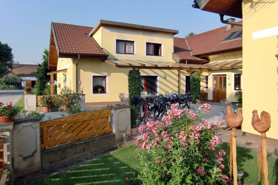 Gelbes Haus mit Garten und Fahrr&auml;dern vor der T&uuml;r.