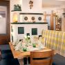 Gemütliches Restaurantinterieur mit Holztisch, Ofen und Dekoration.