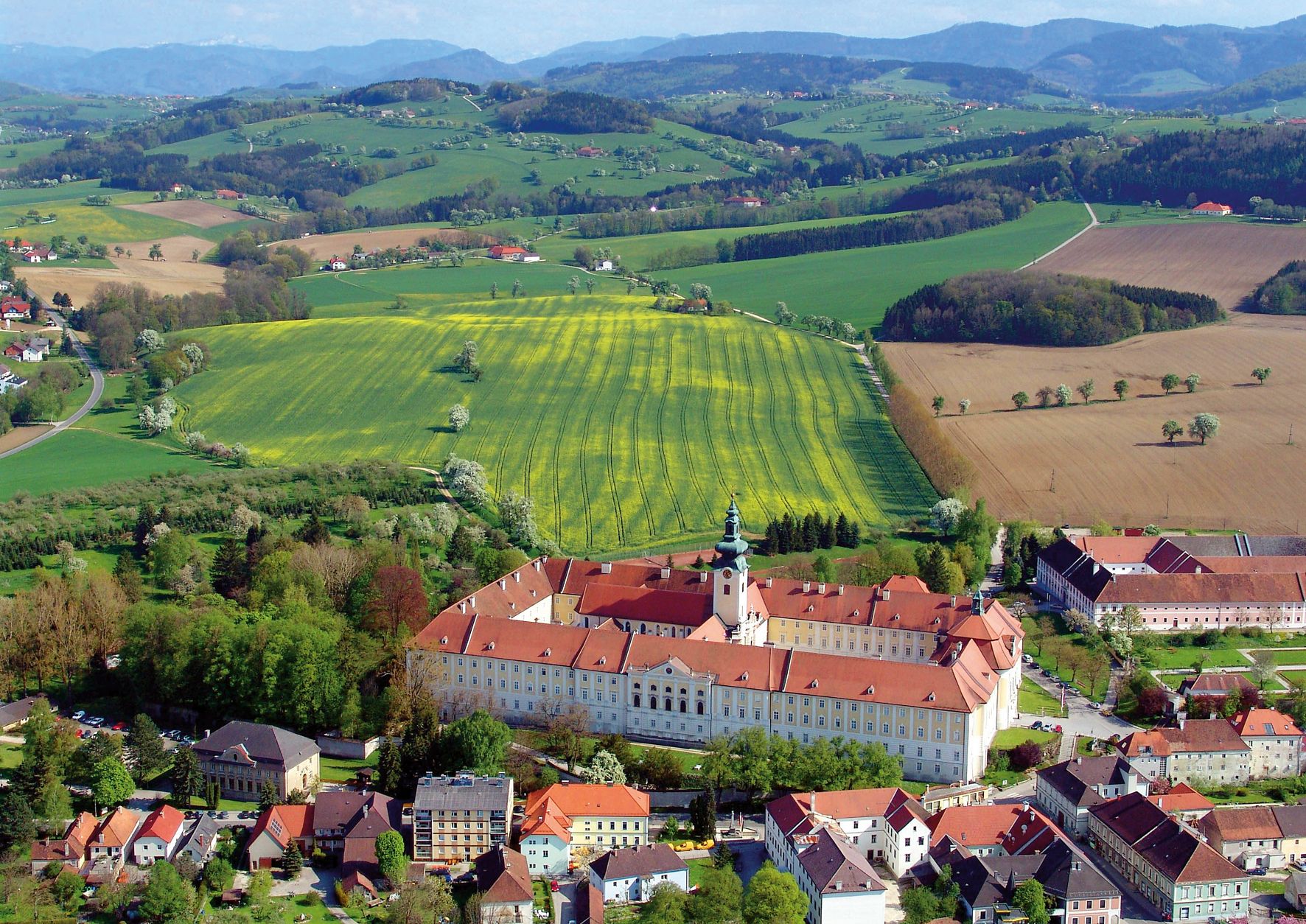 Luftaufnahme des Benediktinerstifts Seitenstetten umgeben von grünen Feldern und Hügeln.