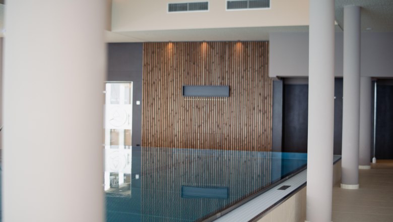 Innenansicht eines Infinitypools im Hotel Schachner mit Holzverkleidung und modernen Säulen.