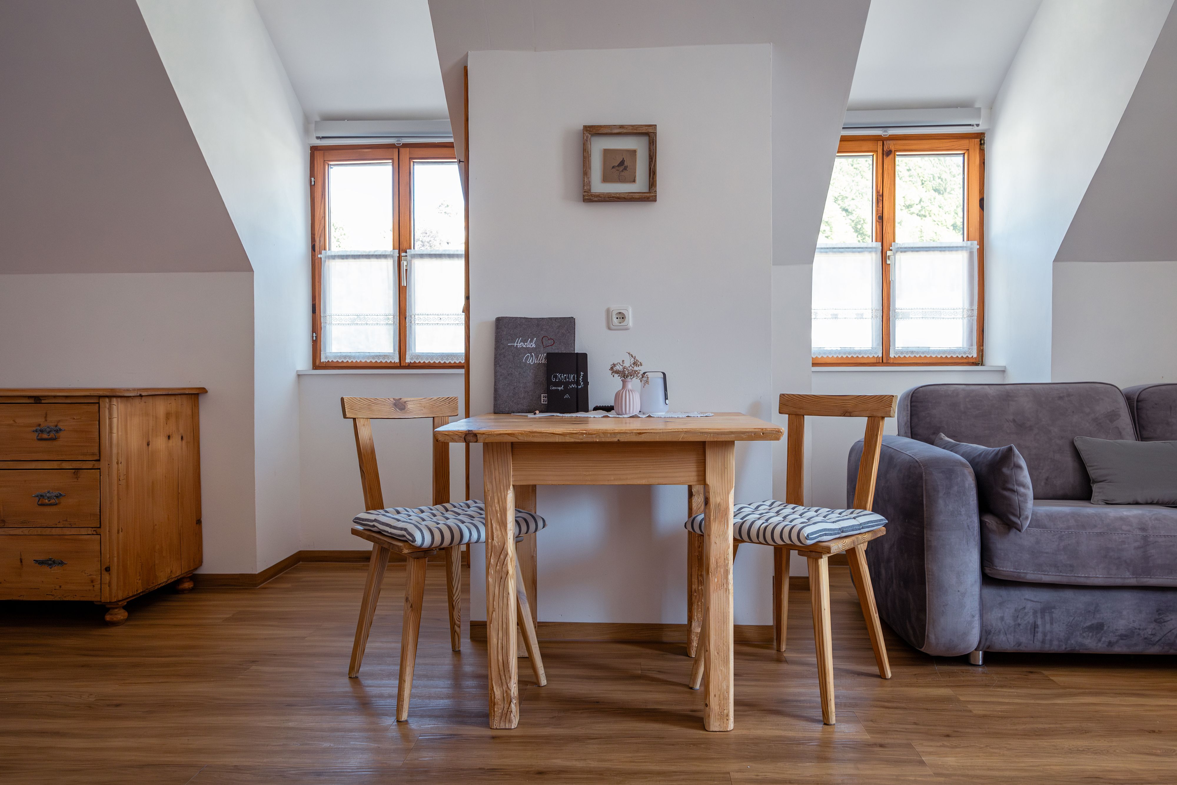 Gemütlicher Wohnbereich mit Holztisch, zwei Stühlen und Sofa.