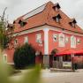 Ein rotes Geb&auml;ude mit roten Sonnenschirmen und Solarpanelen auf dem Dach.