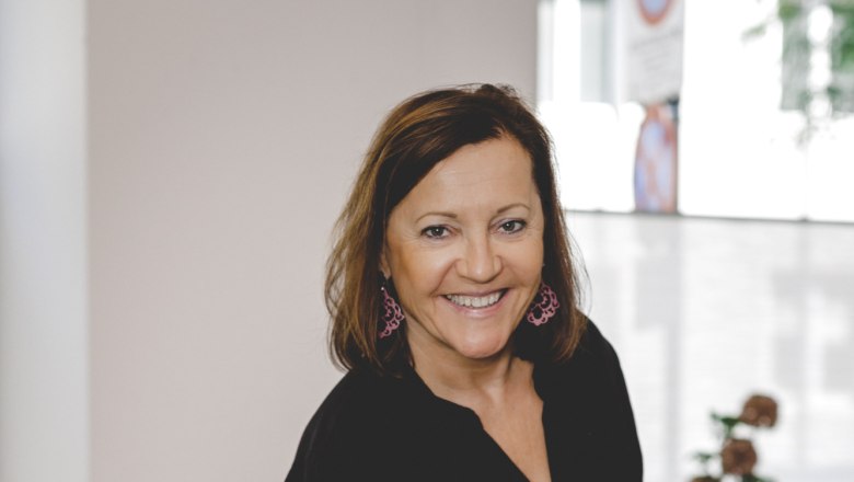 Eine Frau in schwarzer Kleidung serviert ein Gericht mit Tomaten und Fisch in einem Restaurant.