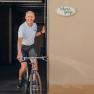 Mann f&auml;hrt Fahrrad aus einer Garage mit Schild 'Fahrrad-Garage'.