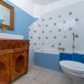 Ein Badezimmer mit blauen Wänden, einer Badewanne, einem Waschbecken auf einem Holzschrank und einem goldenen Spiegel.