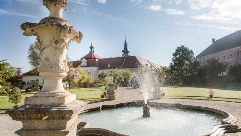 Brunnen im Garten des Stifts Seitenstetten mit barocker Architektur im Hintergrund.
