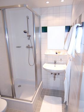 Kleines Badezimmer mit Dusche, Waschbecken und Handtüchern.