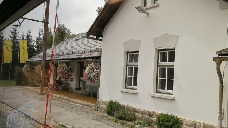 Bahnhof Mitterbach mit weißem Gebäude und Blumen.