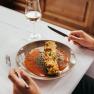 Gef&uuml;llte Zucchini mit Tomatensauce auf einem Teller, daneben ein Glas Wei&szlig;wein.