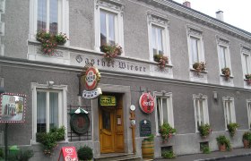 Fassade des Gasthofs Wieser mit Blumenk&auml;sten und Werbeschildern.