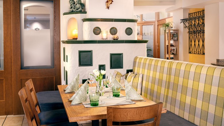 Gemütliches Restaurantinterieur mit Holztisch, Ofen und Dekoration.