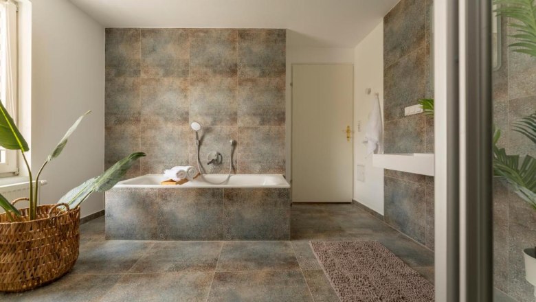 Modernes Badezimmer mit Badewanne, Pflanzen und Handtuch.