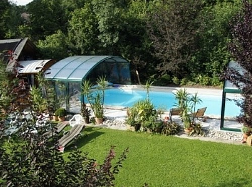 Pension Landhaus Ingrid, © Pension Landhaus Ingrid Ein überdachter Außenpool mit Liegestühlen und Pflanzen, umgeben von grüner Landschaft.