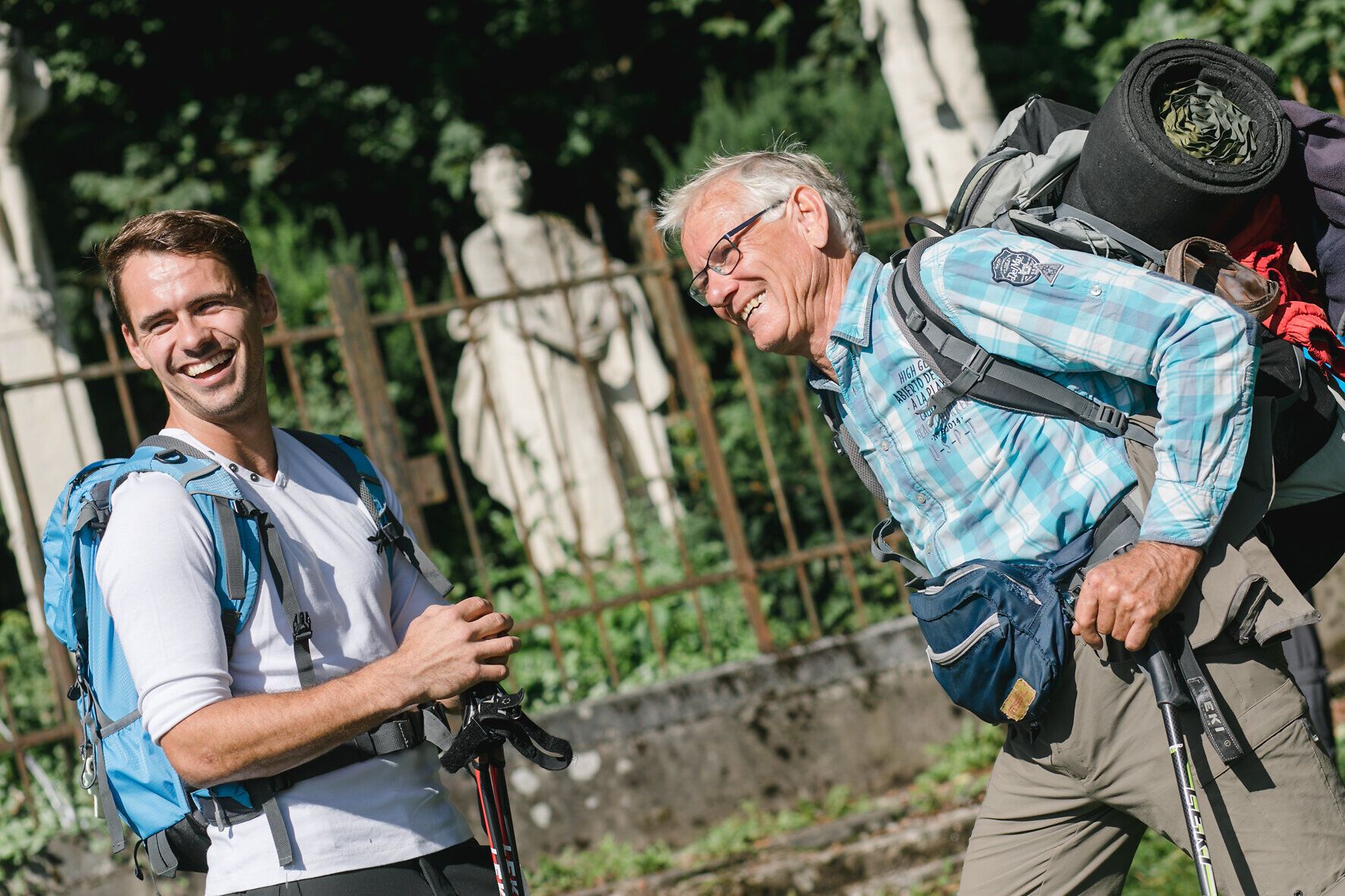 Zwei Wanderer lachen und genießen die frische Bergluft, während sie auf dem Manker Wallfahrerweg unterwegs sind. Umgeben von üppigem Grün und majestätischen Bäumen, strahlt die Szenerie eine einladende Atmosphäre aus, die zum Entdecken und Verweilen einlädt.