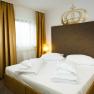 Ein Doppelzimmer mit einem großen Bett, goldenen Vorhängen und zwei Nachttischen mit Lampen.