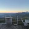 Terrasse mit Holzm&ouml;beln und Bergblick bei Sonnenaufgang.