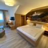 Modernes Hotelzimmer mit Doppelbett, Schreibtisch, Fernseher und gro&szlig;em Wandbild.
