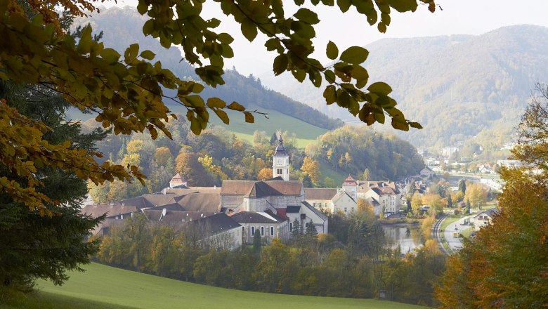 Stift Lilienfeld im Herbst mit buntem Laub und umliegenden Hügeln.