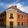 Ein traditionelles Gasthaus mit orange-gelber Fassade und roten Dachziegeln unter blauem Himmel.