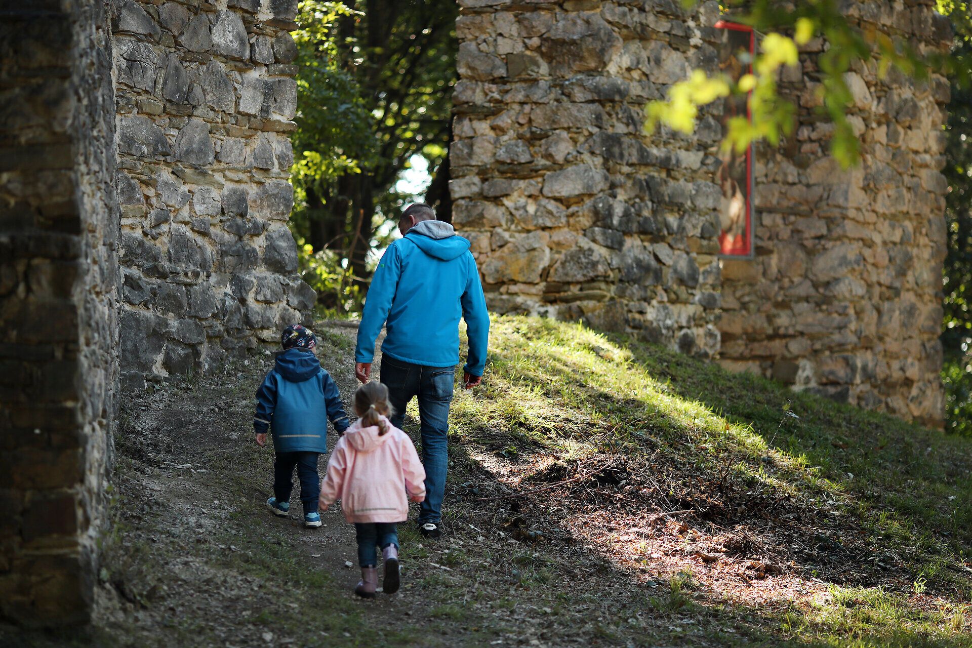 Ein Vater wandert mit seinen beiden Kindern durch den Triumphbogen im Naturpark Sparbach.