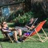 Drei Personen entspannen auf Liegestühlen im Garten.