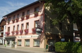 Ein traditionelles Gasthaus mit rosa Fassade und Blumenkästen an den Fenstern.